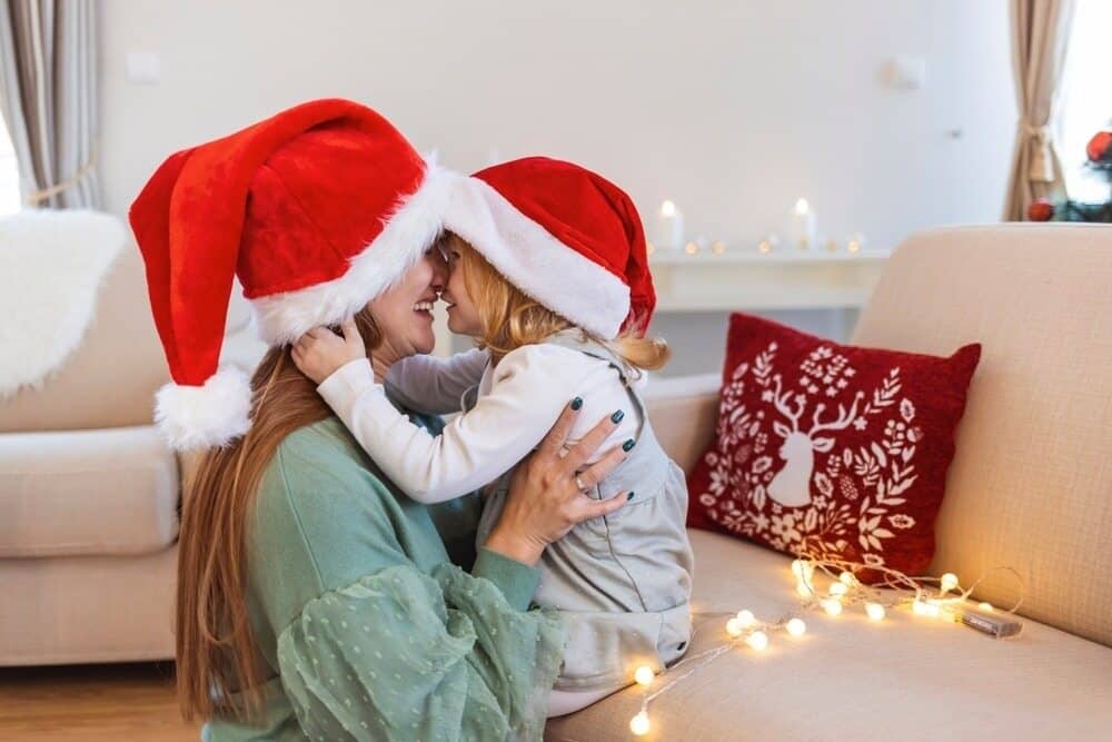 Mother hugging her child with santa hats on at Christmas time